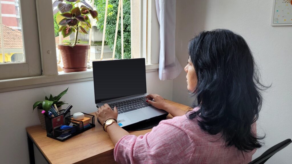 Nathalia escribiendo en su laptop junto a una ventana